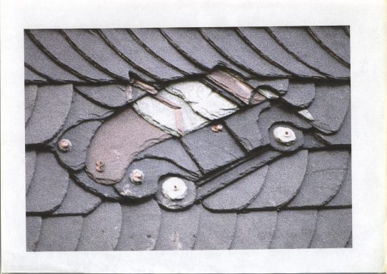 VW Käfer Ein Auto aus Dachziegeln gestaltet, integriert in ein Dachmuster.
