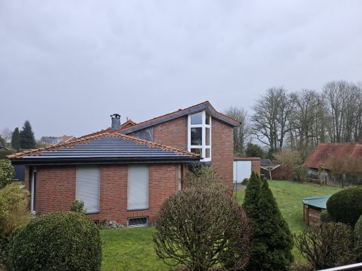 Steildach Rotes Backsteinhaus mit Satteldach, umgeben von Bäumen und Rasenflächen.