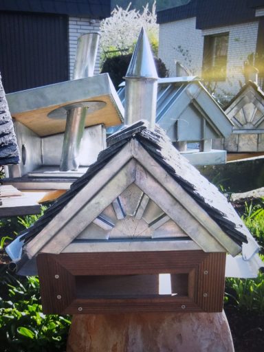 Vogelhäuser Holzvogelhaus mit spitzem Dach und detaillierten Verzierungen im Hintergrund.